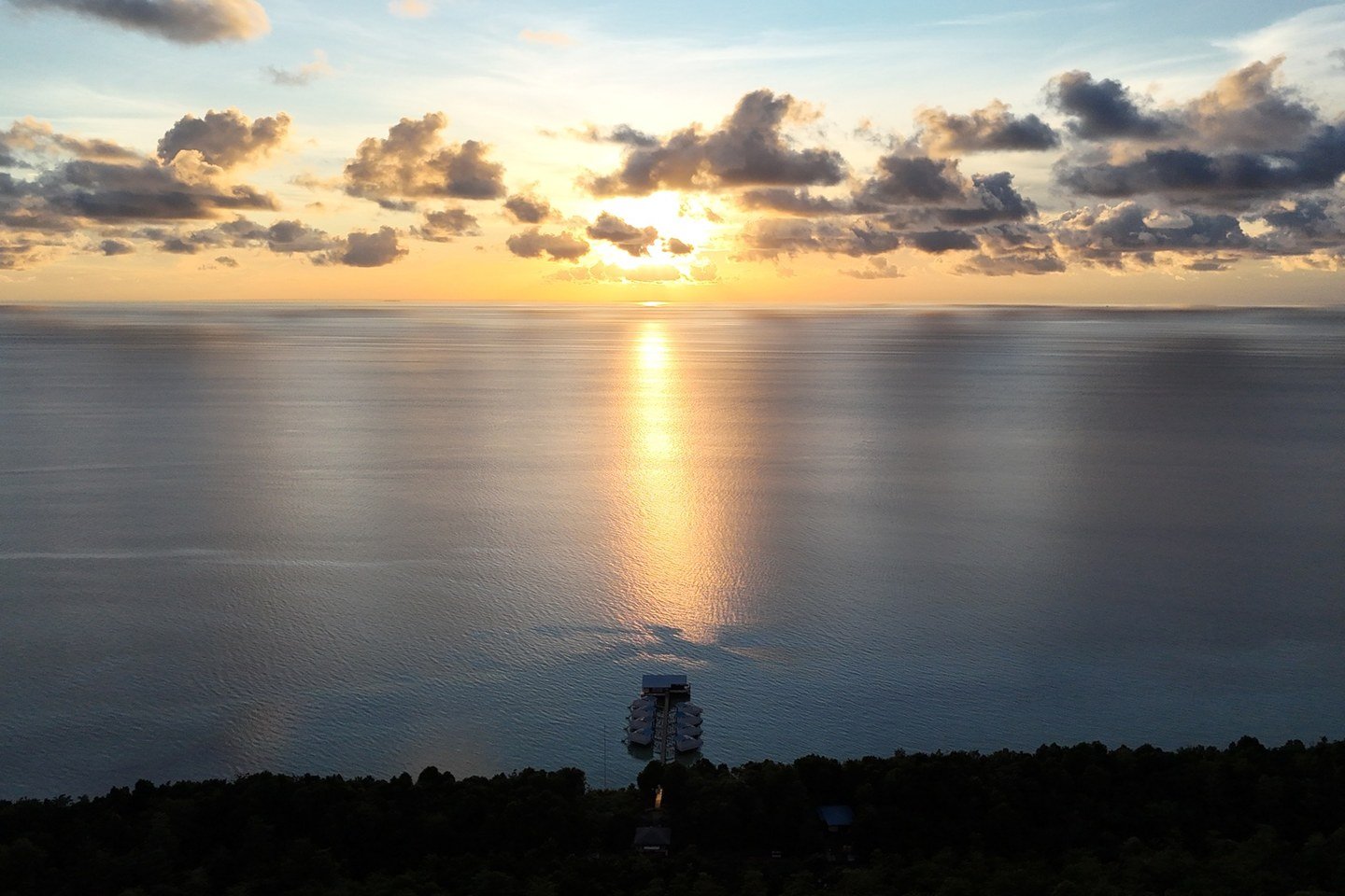 Aerial view of Arasatu's overwater villas as evening light reaches the reef.