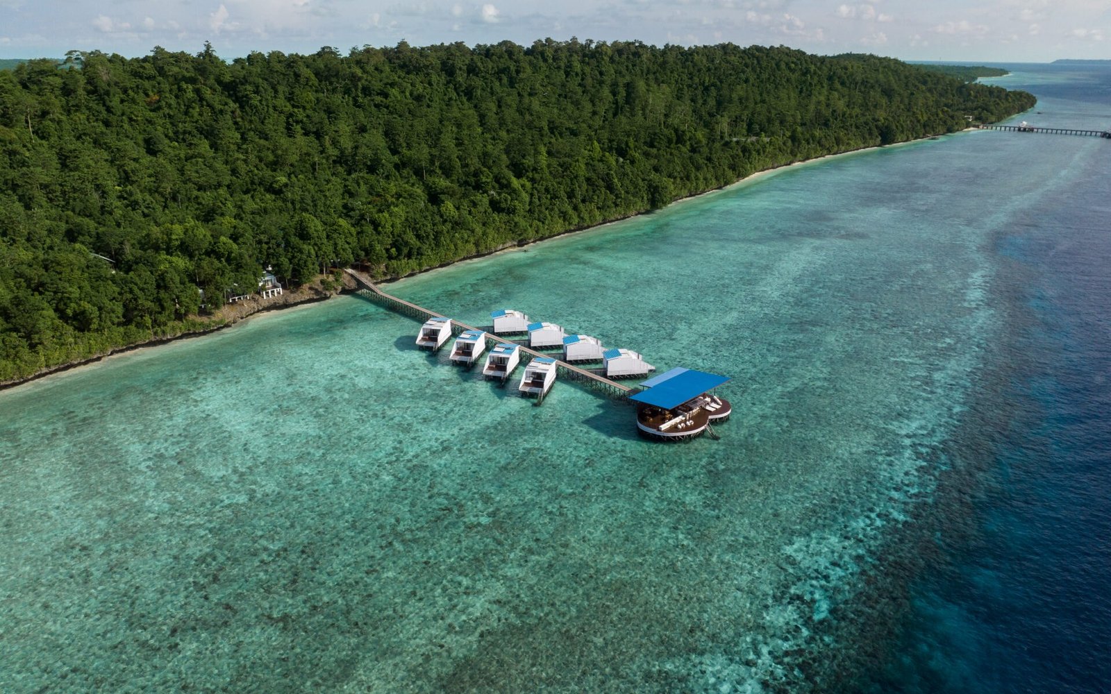 Arasatu's overwater villas beside Maratua's forest and broad coral shelf.