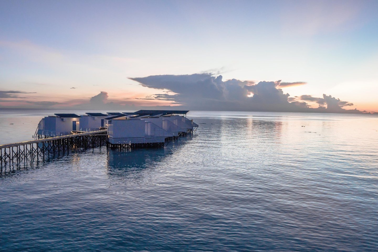 Arasatu's Floating Villas aligned above clear coral-rich water.