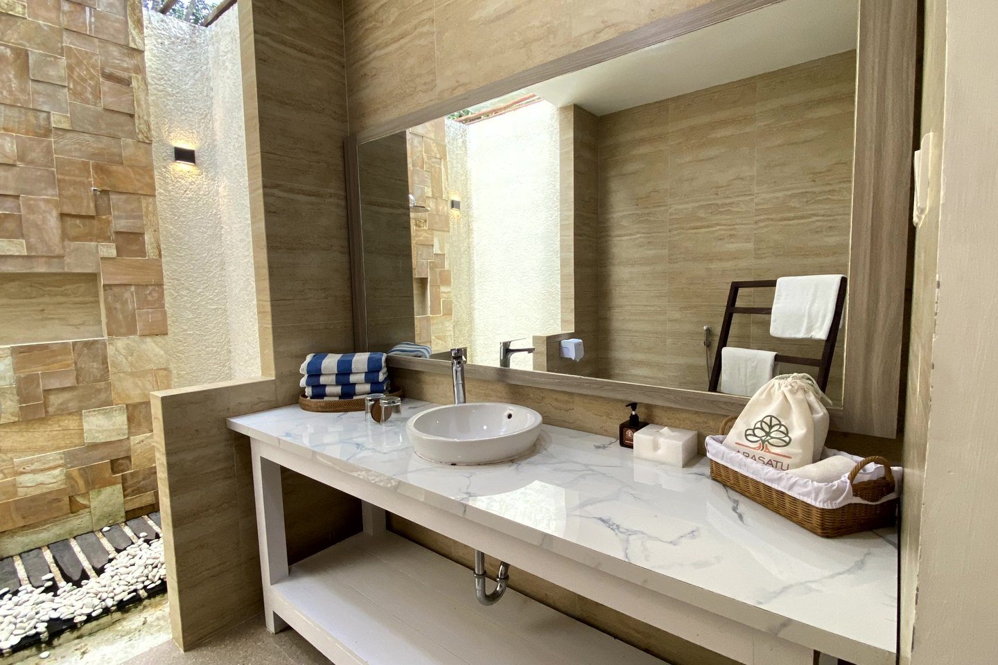 Open-air shower and vanity inside an Arasatu villa bathroom.