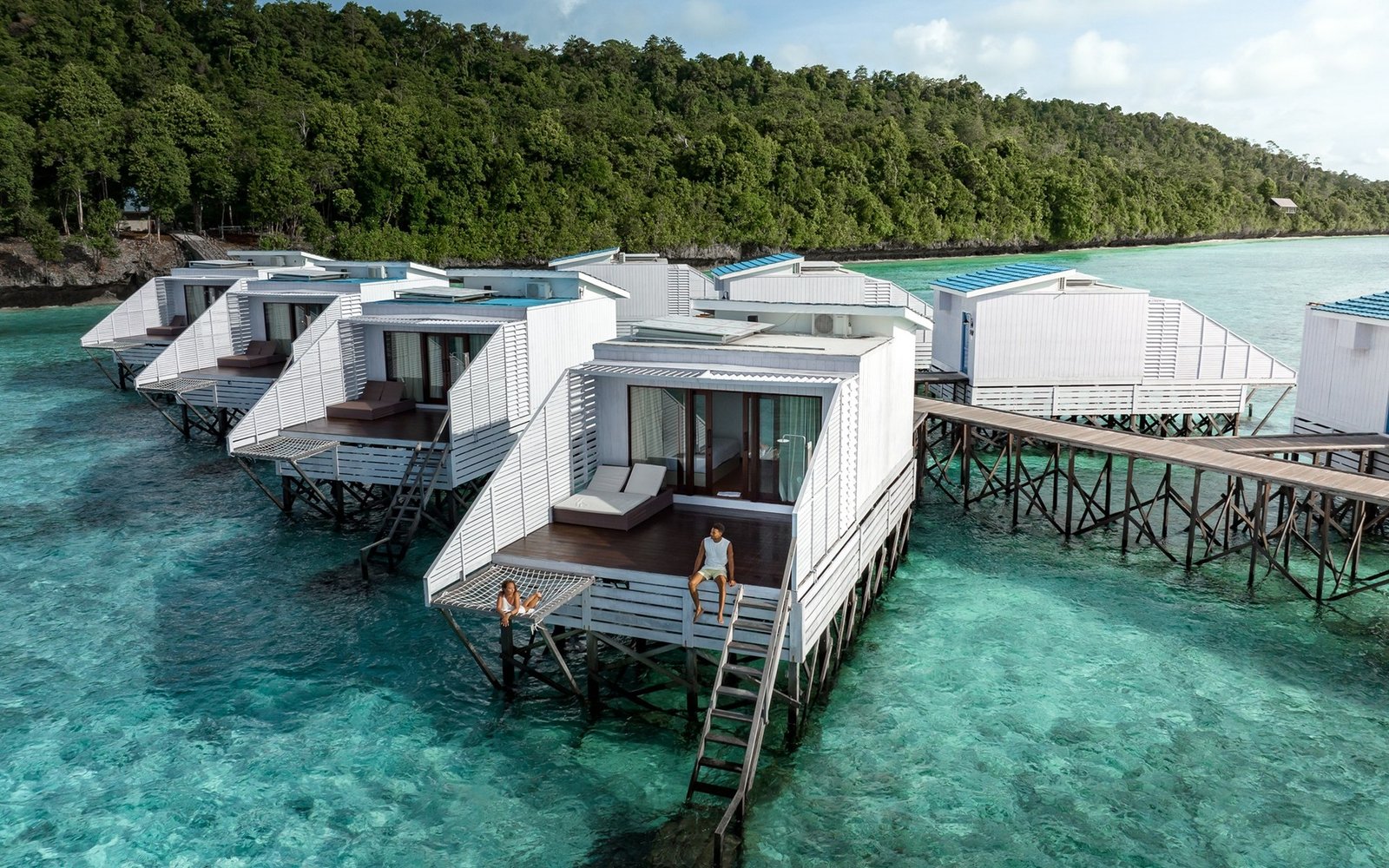 Guests relaxing on a Floating Villa deck above coral-rich water at Arasatu.