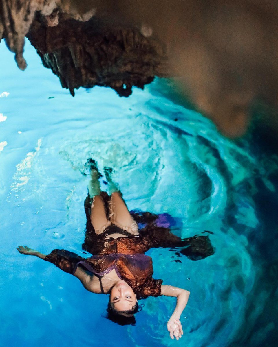 A guest floating in clear blue water inside Halo Tabung Cave near Maratua.
