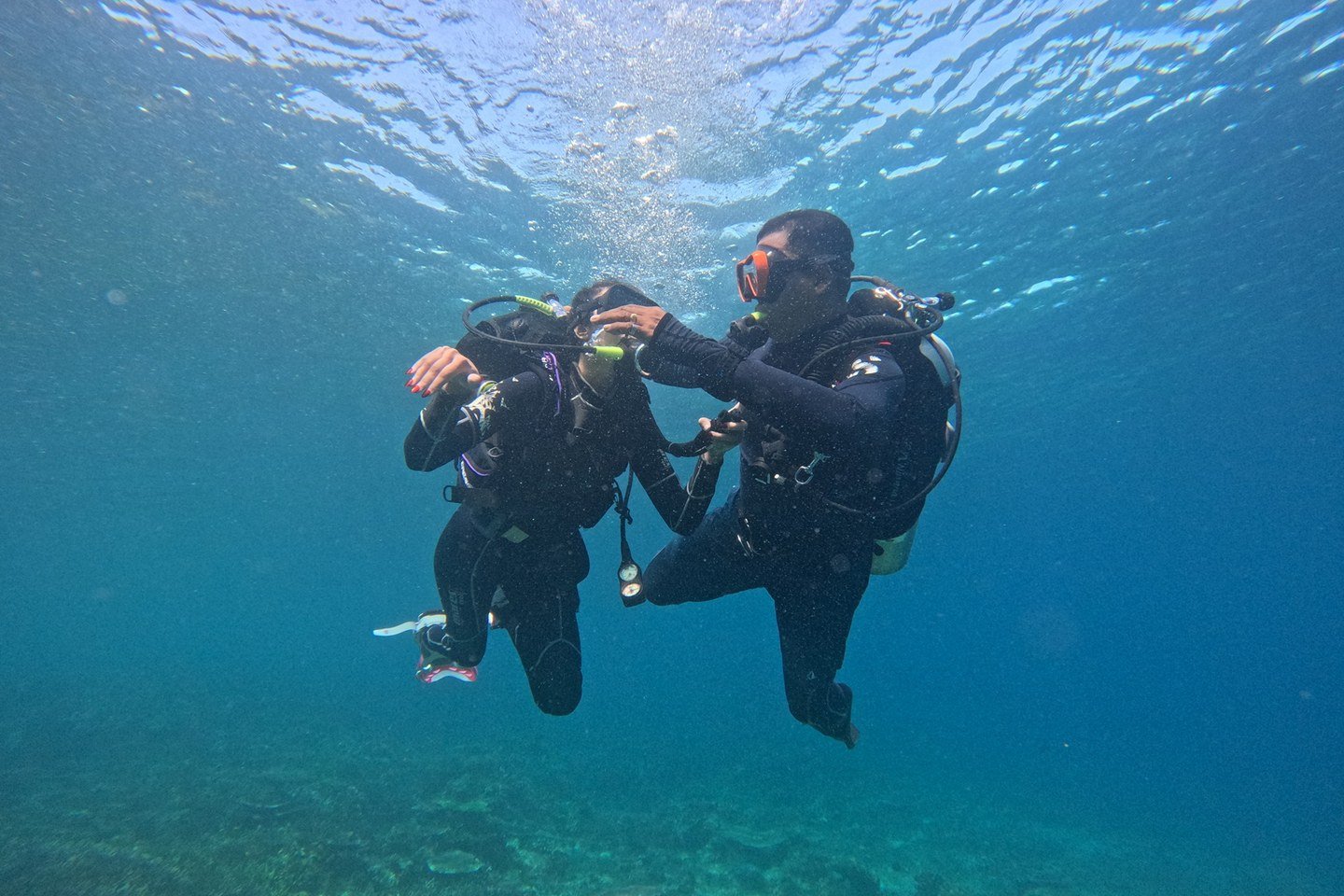 A dive professional guiding a guest through an introductory scuba experience in clear water.