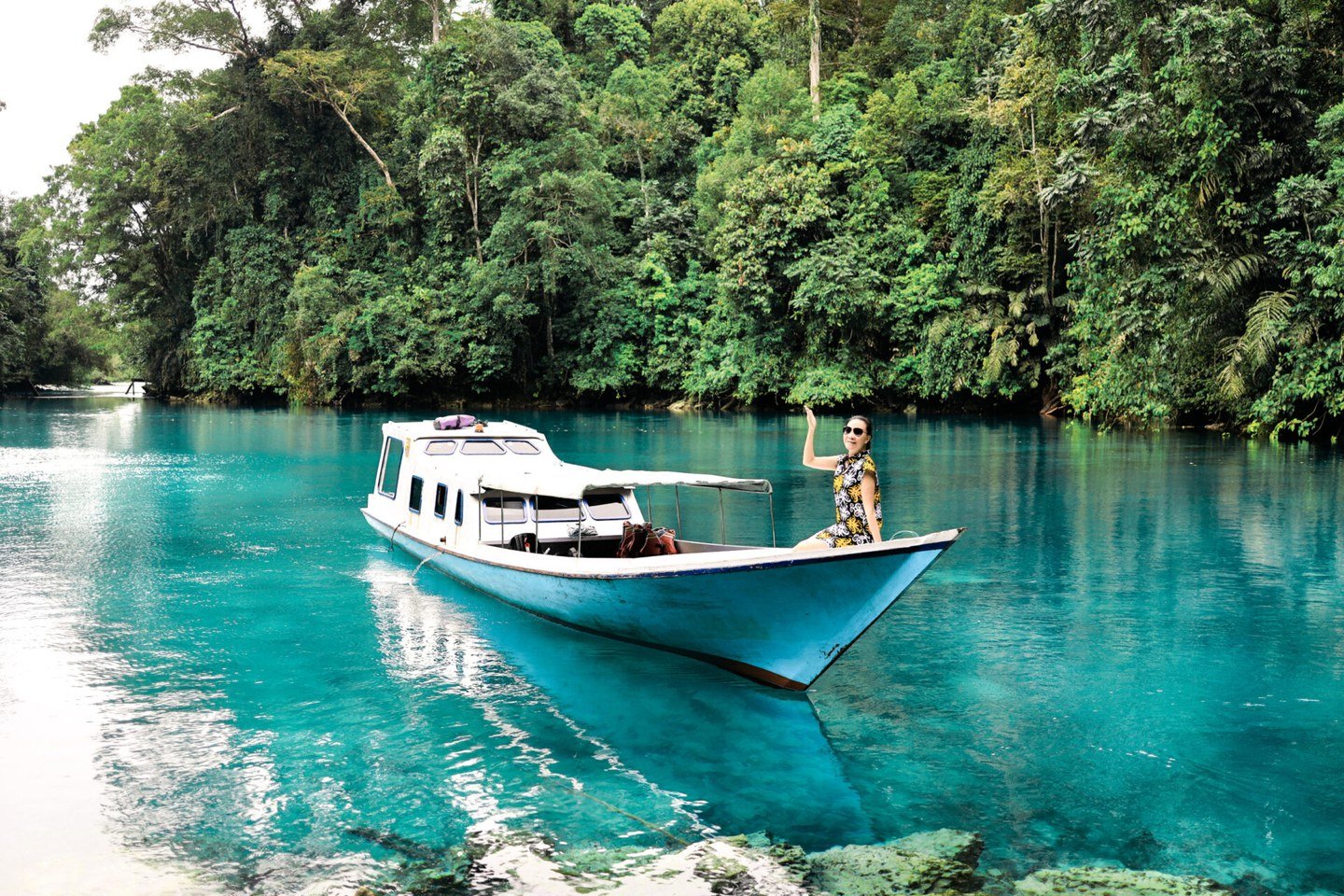 A guest aboard a local boat on the clear turquoise water of Labuan Cermin.